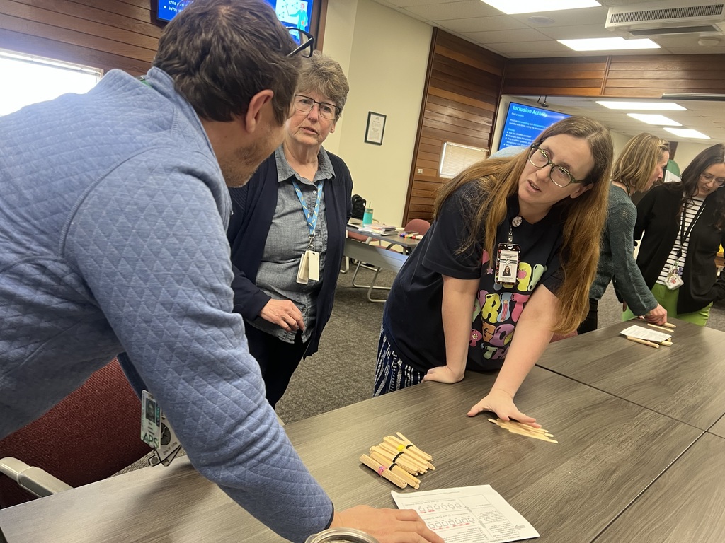 Teachers discuss student look fors as they practice a place value activity with bundles of popsicle sticks