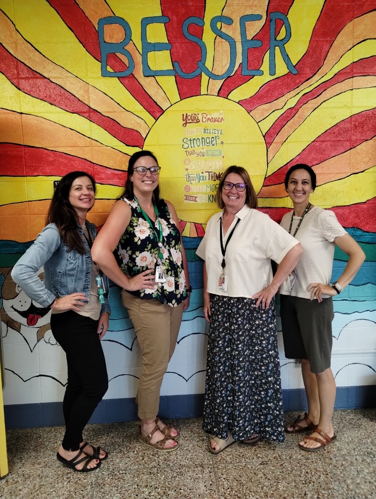 School psychologist, school social worker, speech pathologist, and teacher consultant pose in front of the Besser Elementary School wall mural.