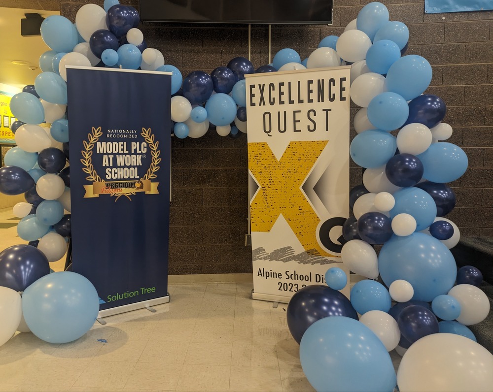 banner of 'model PLC at Work School' and banner of 'excellence quest' theme surrounded by balloons