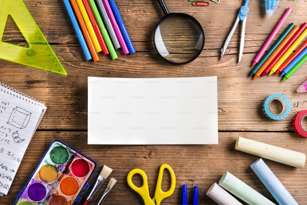 A blank paper is surrounded by school supplies