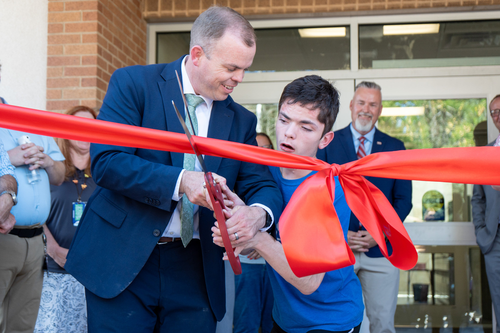 Principal and Student cut the ribbon in front of new campus.