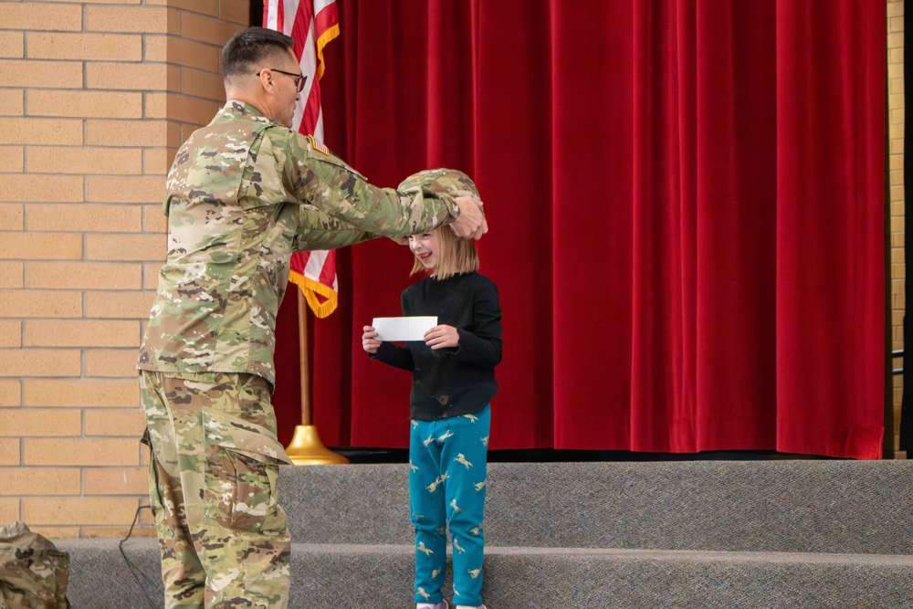 a young student wears a combat helmet at a school assembly