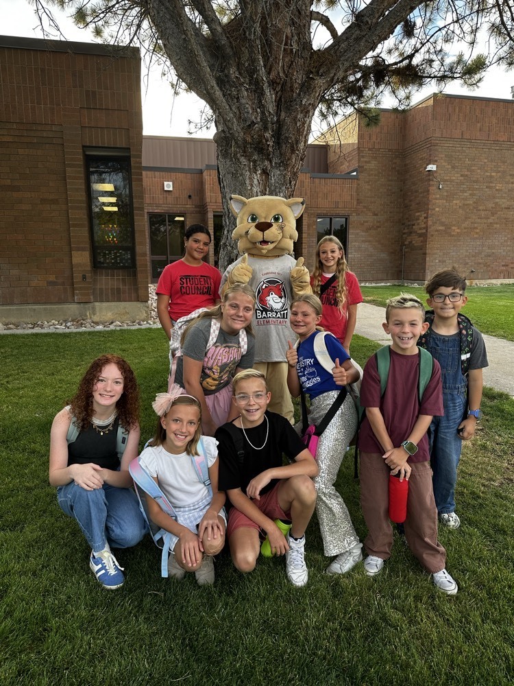 students and a mascot standing by a tree