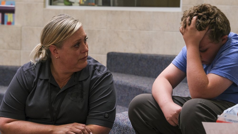 Teacher sitting with a sad child.