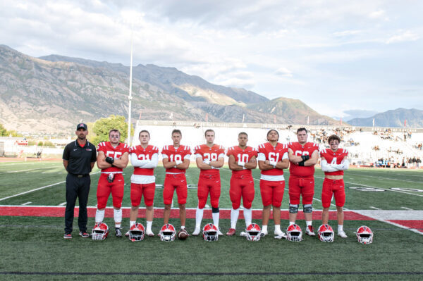 Coach Behm standing with seniors in football gear.