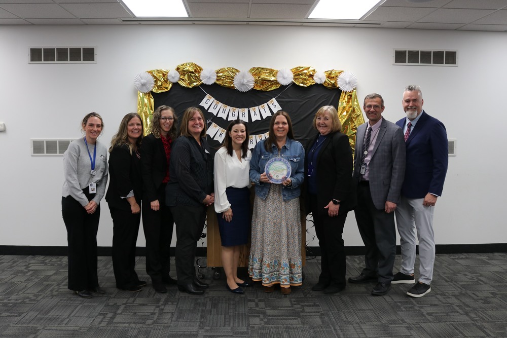 Kerry milner holding her award posed with USBE reps and district admin