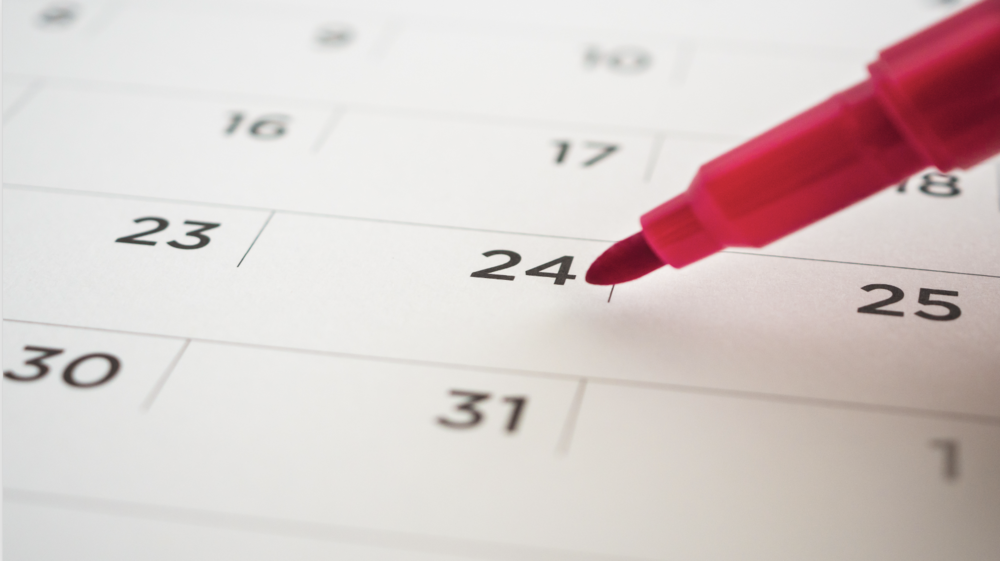 Printed Calendar with a red tip felt pen pointing to a date