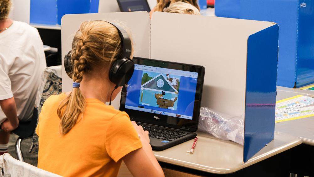 an elementary school student using a computer with headphones