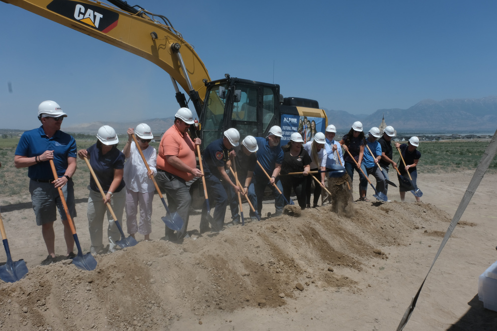 ASD personnel and guests shovel dirt at the construction site of a new high school