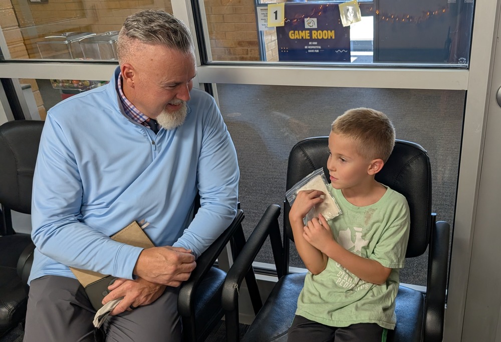 superintendent sits with a young student
