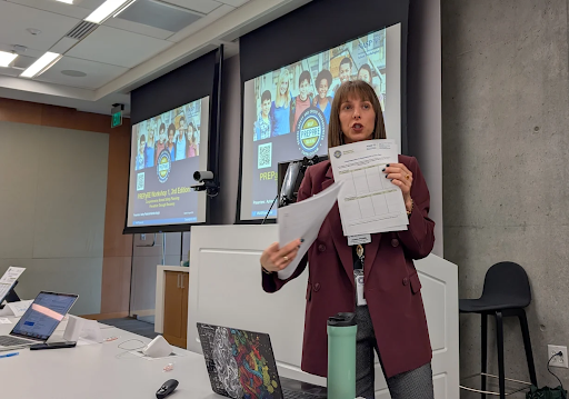 Photo showing a woman giving a presentation in front of a large projector screen.