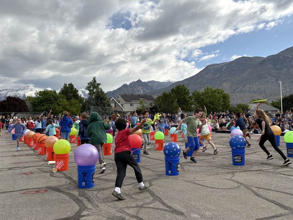 Students running around buckets with large balls on top of the buckets