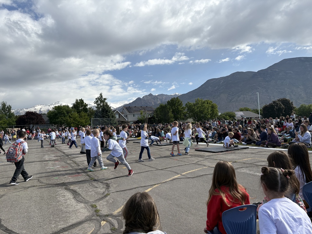 students in white shirts standing on the blacktop
