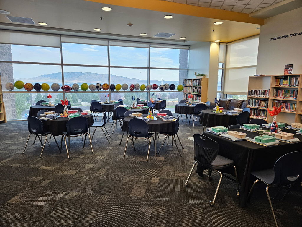 picture of a room with tables and chairs set with school supplies