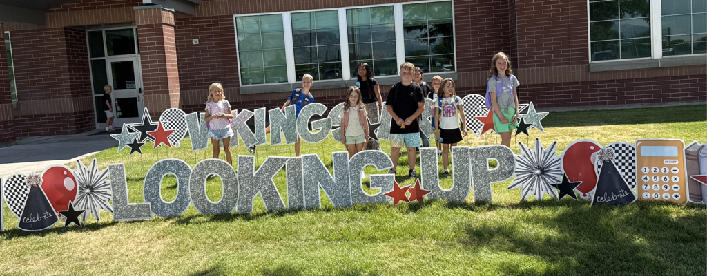 Vineyard students standing in front of a yard sign that says Vikings are looking up
