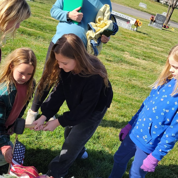 students placing flags on veteran graves