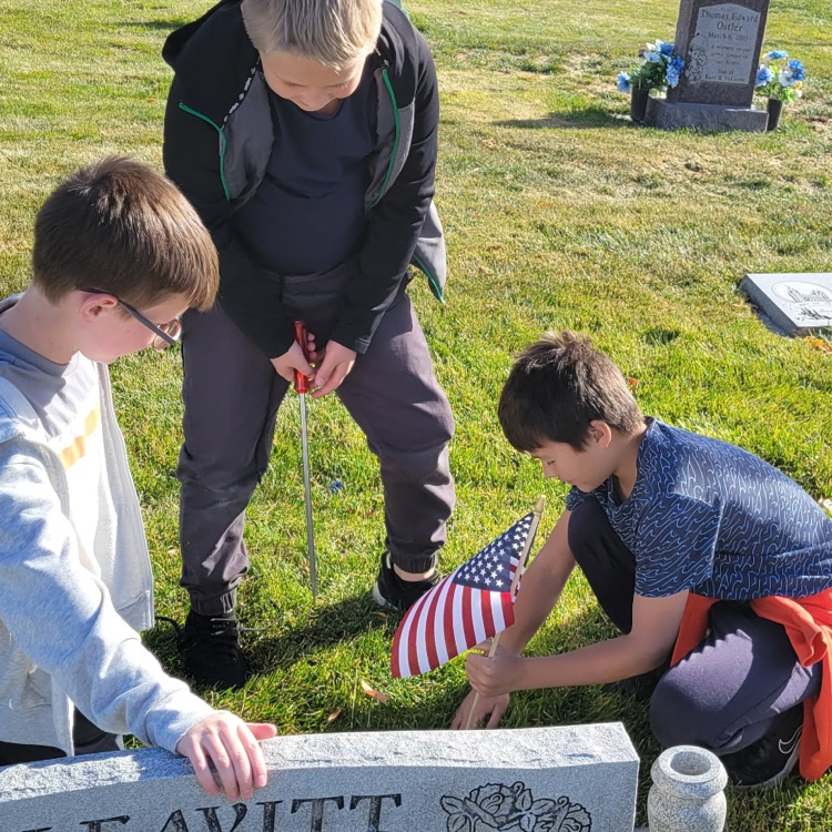 students placing flags on veteran graves