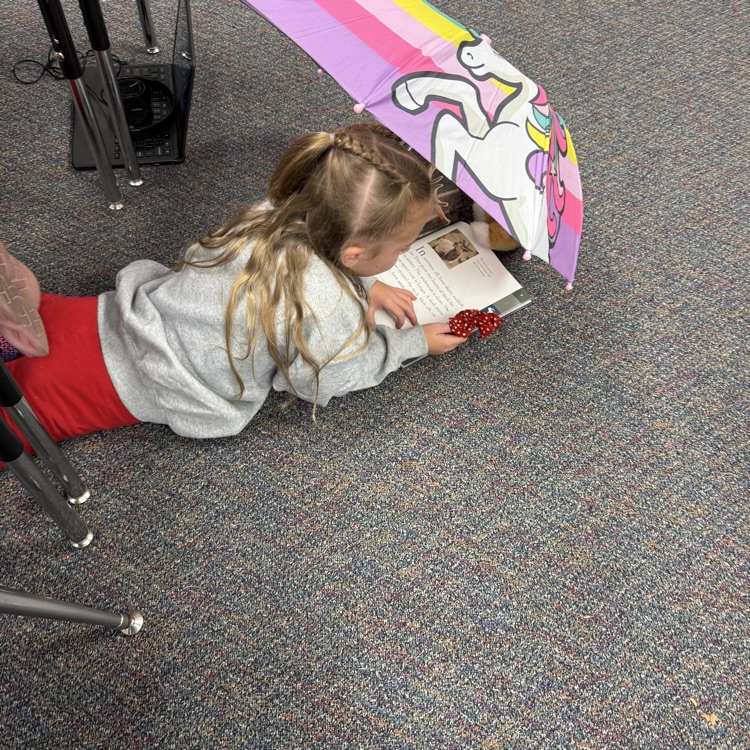 student laying on ground with a book