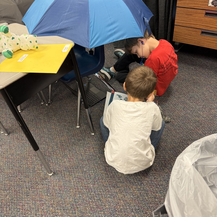 students sitting under an umbrella