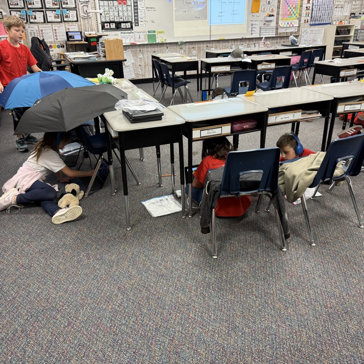 students sitting under desks