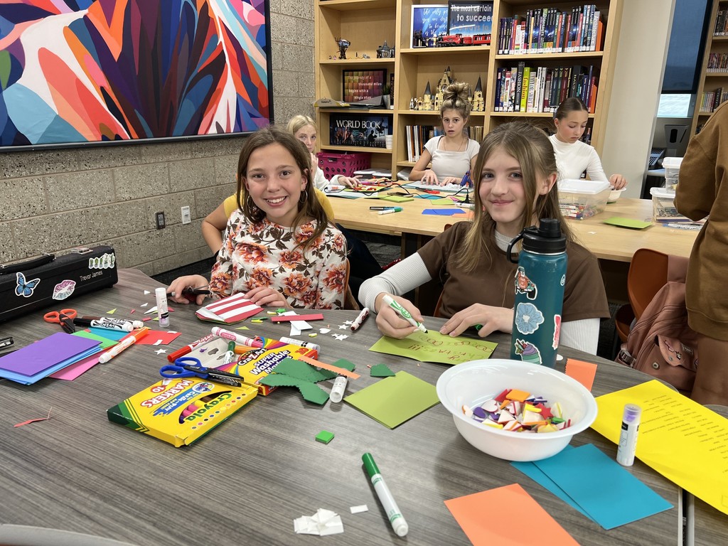 Students in the library showing craft projects they made.