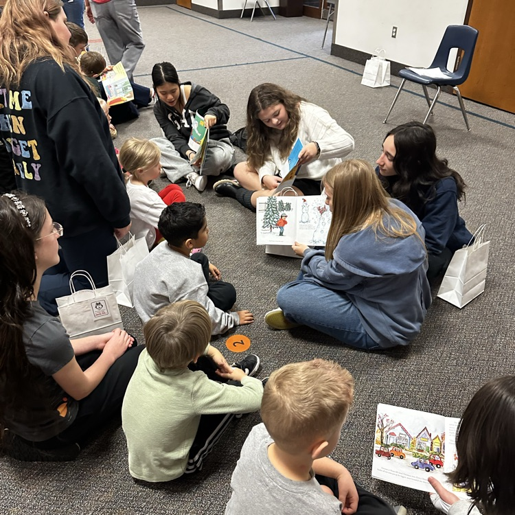 junior high students reading books to kindergartners