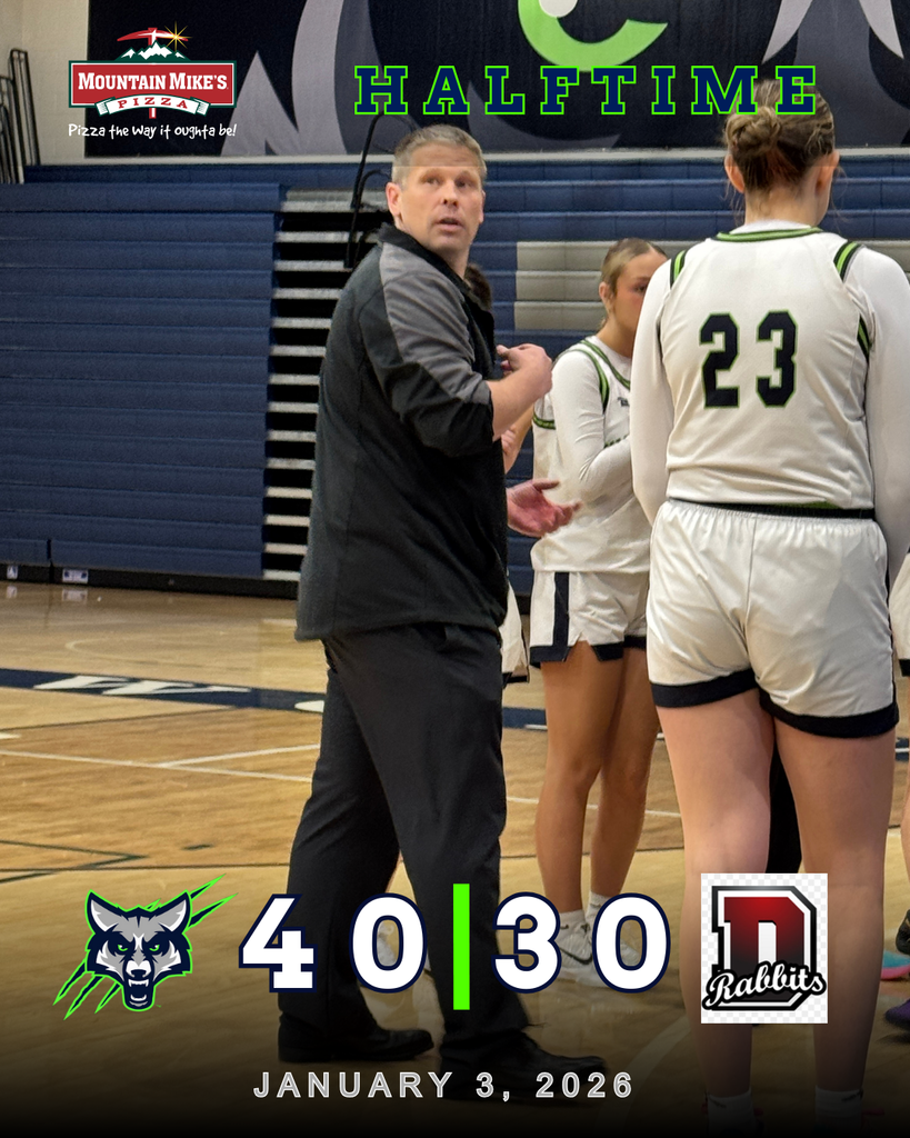 Girls basketball team huddles around their coach during a halftime timeout on the home court at Timpanogos High School. A graphic overlay shows the T-Wolves leading 40–30 at halftime against the Rabbits, with sponsor Mountain Mike’s Pizza displayed at the top.
