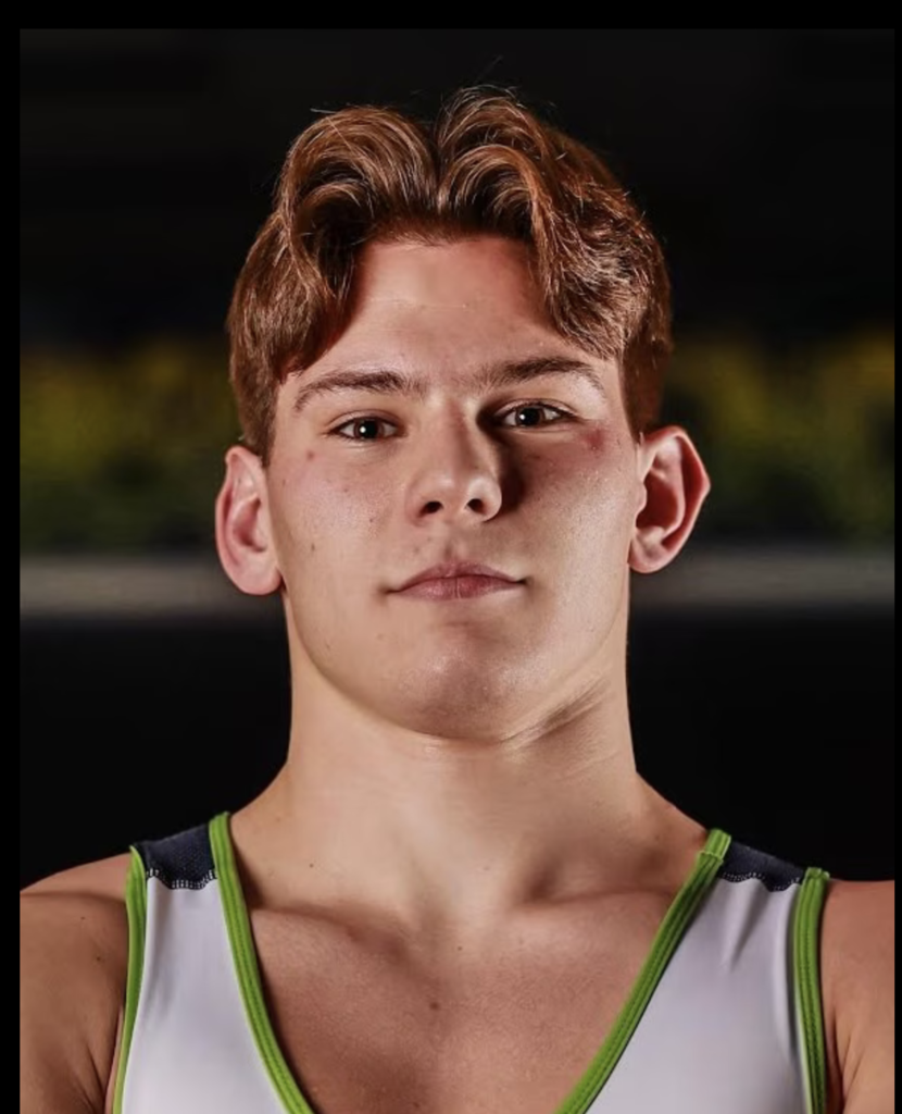 Kaleb Midzinksi, a Timpanogos High School wrestler, poses for a portrait wearing a wrestling singlet with green trim, looking directly at the camera with a focused, confident expression against a dark background.