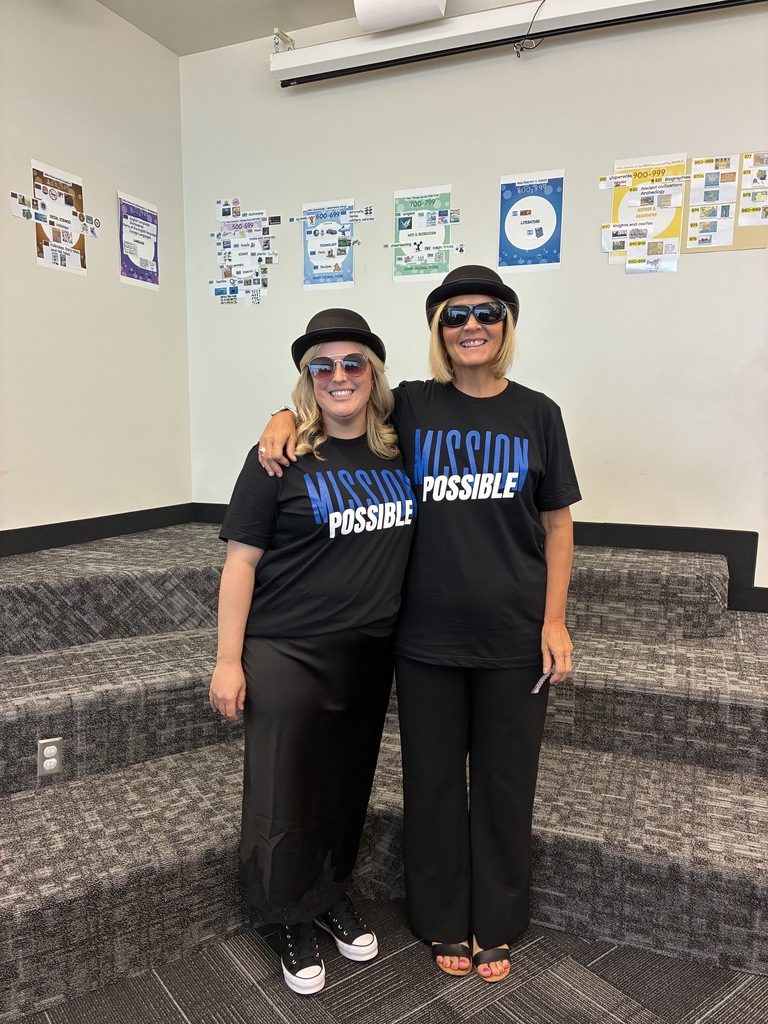 Image of two women dressed as spies wearing a shirt that says Mission: Possible!irt that says Mission: Possible