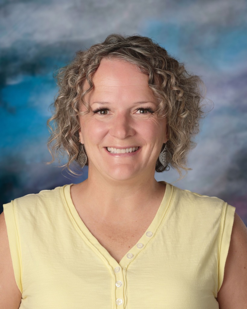 Picture of April Felix, school counselor. She is wearing a yellow v-neck shirt, has a big smile, and short curly hair. 