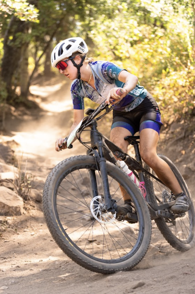 Student on Mountain Bike riding down a step dirt trail