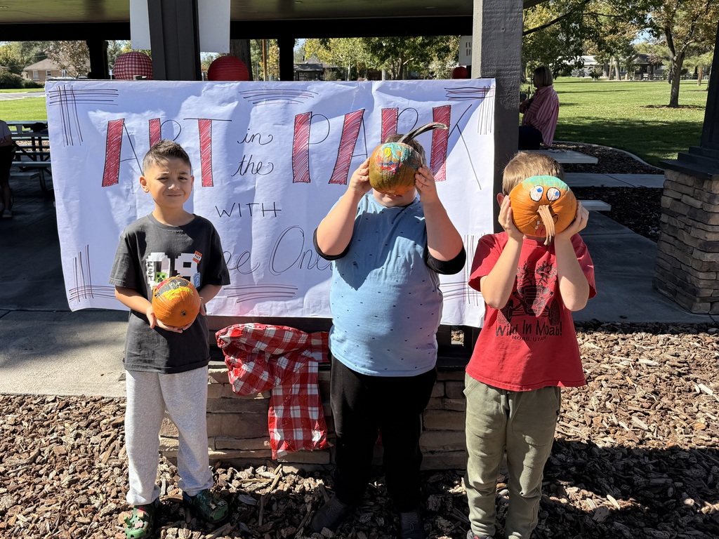 Three boys holding up painted pumpkins. 