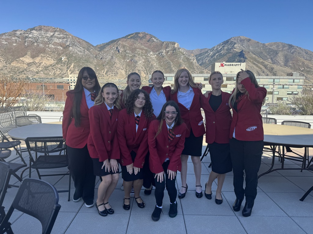 Students in red suit jackets and ties posing for a picture