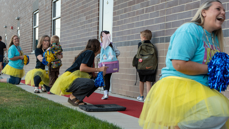 Kindergarten teachers welcome new students walking on a red carpet