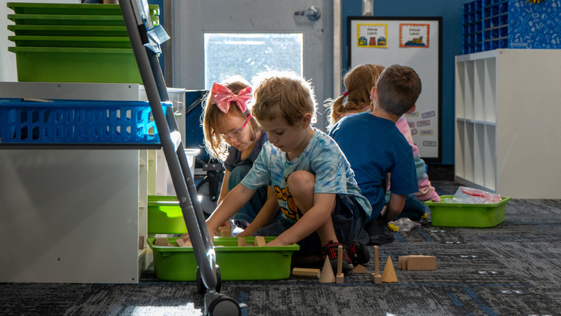 Kids playing with blocks on the ground  just inside their classroom door