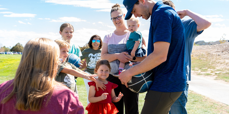 Jimmer Fredette signing a basketball with the family that he is donating the ball and hoop to