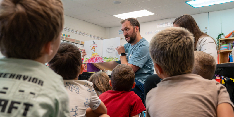 Volunteer reading a book to elementary children