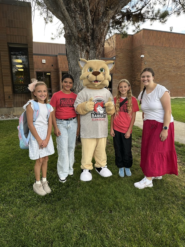 students and a mascot standing by a tree
