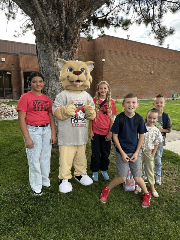 students and a mascot standing by a tree
