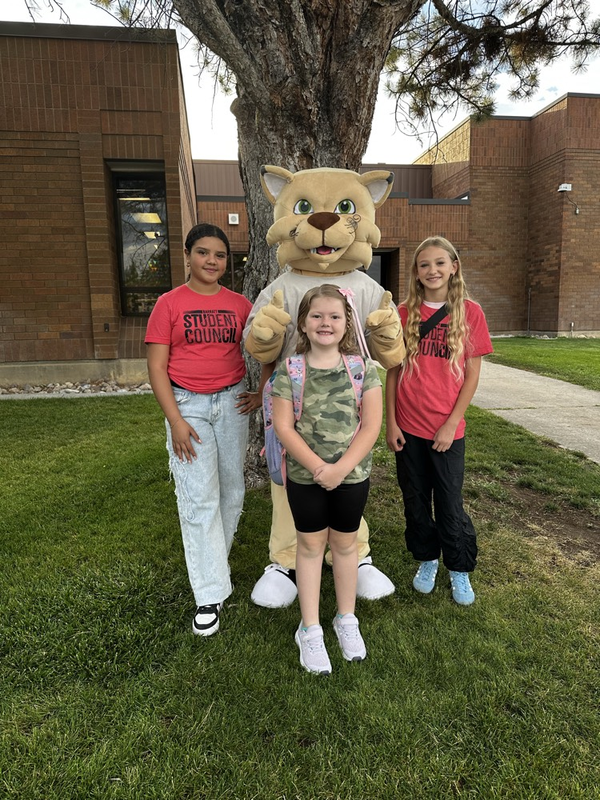 students and a mascot standing by a tree