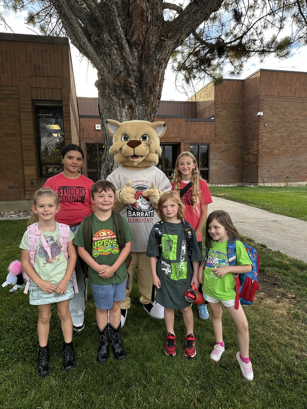 students and a mascot standing by a tree