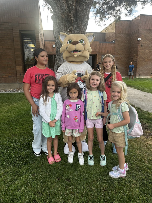 students and a mascot standing by a tree