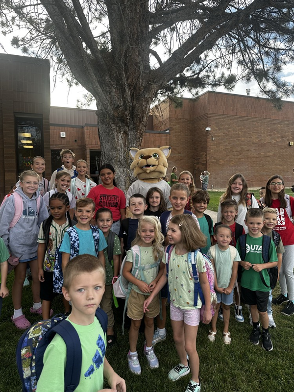 students and a mascot standing by a tree