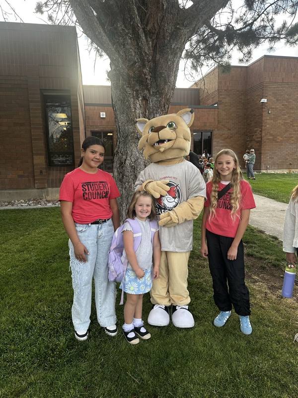 students and a mascot standing by a tree