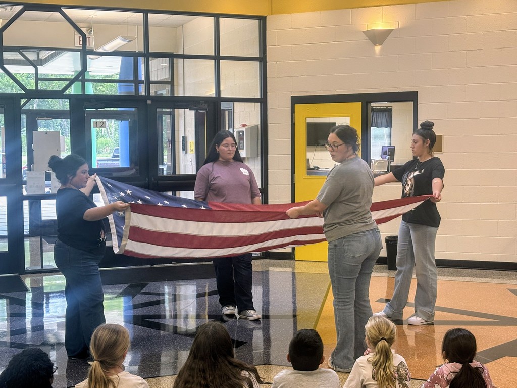 teenagers demonstrating how to properly fold the flag to fourth graders