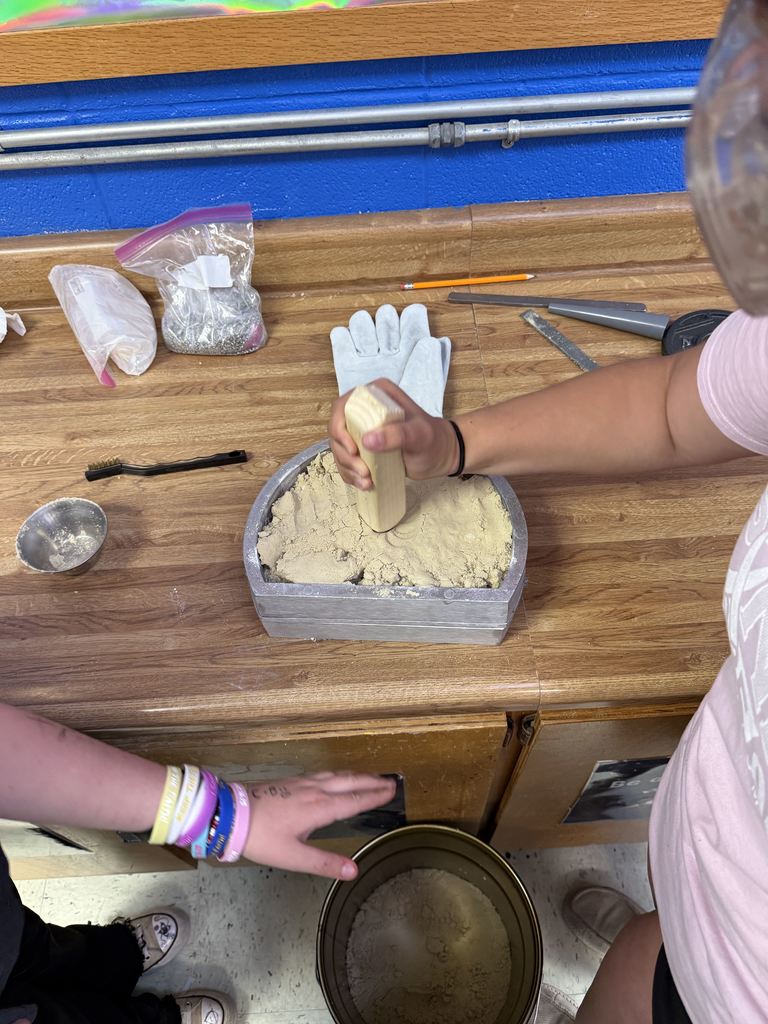 Students helping fill and tamp the mold with sand
