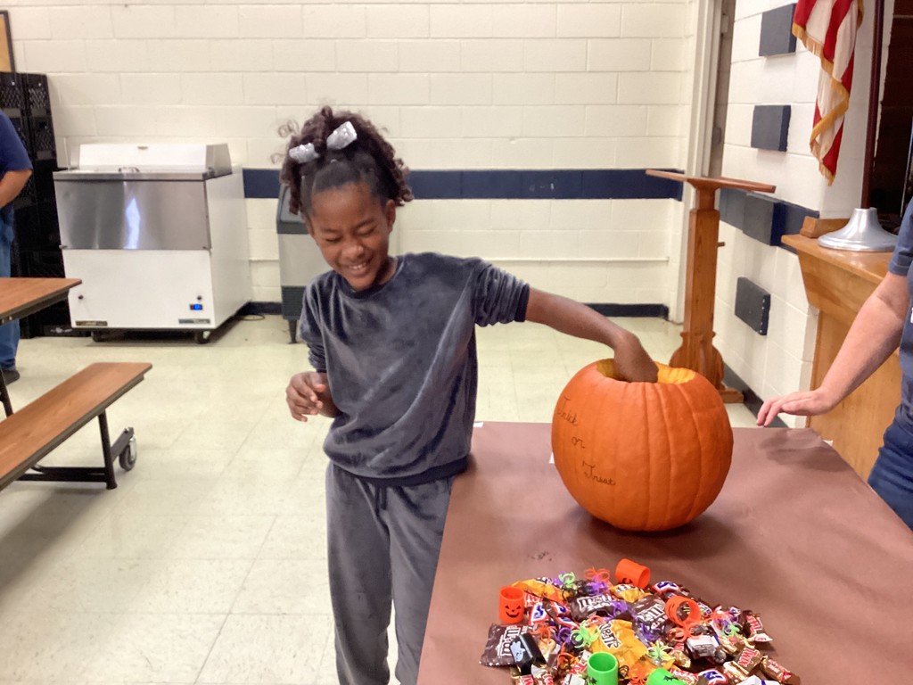 Student reaching into a pumpkin. 