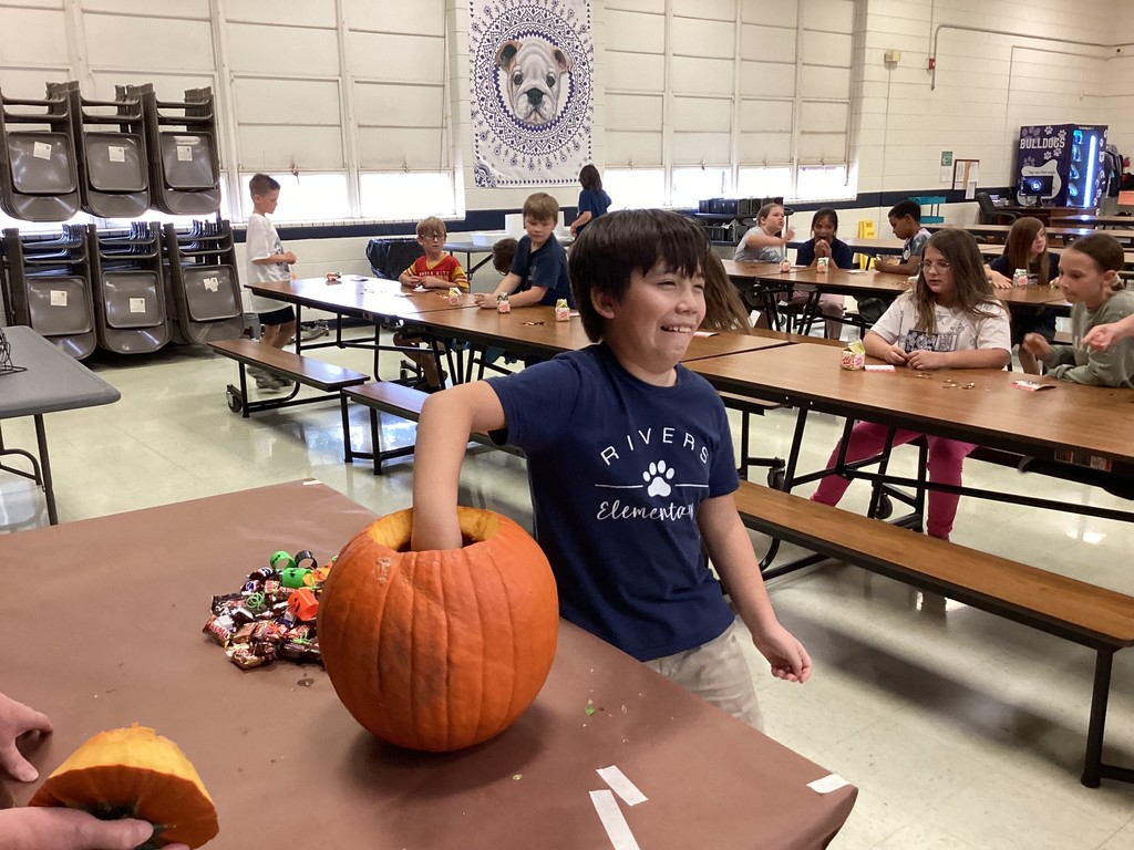 Student reaching into a pumpkin. 