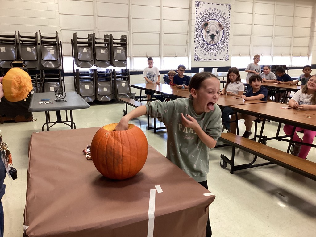Student reaching into a pumpkin. 