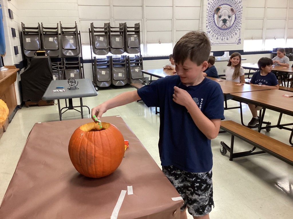 Student reaching into a pumpkin. 